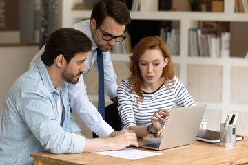 Three 30s colleagues using laptop discussing online presentation, prepare collaborative on-line project, make computer task, share ideas consider strategy, develop start up, plan work sit at workplace