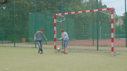 Teenagers play ball on the soccer field. Down syndrome boy catches a ball. Goal scored. Camera movement.