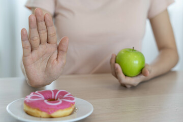 Good health food and diet. Women reject junk food or unhealthy foods such as donut and choose healthy foods such as green apple.