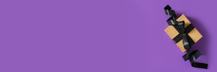 Halloween and black friday gift box with ribbon on purple background