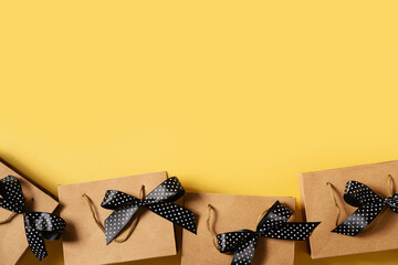 Black friday concept with paper craft package row and black bow on yellow background