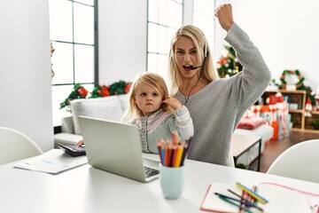 Mother of caucasian daughter wearing call center agent headset at home annoyed and frustrated shouting with anger, yelling crazy with anger and hand raised