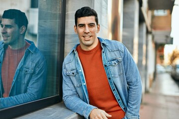 Young hispanic man smiling happy standing at the city.