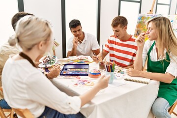 Group of people smiling happy drawing sitting on the table at art studio.