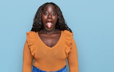 Young african woman wearing casual clothes sticking tongue out happy with funny expression. emotion...