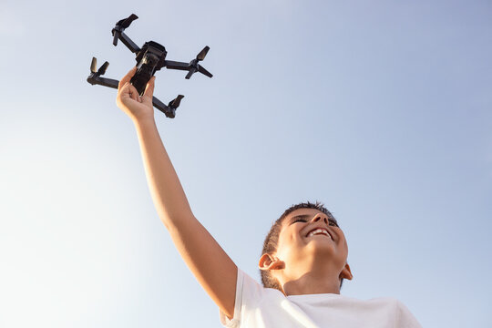 Smiling boy holds a drone from below at sunset.
Conceptual of lifestyle, technology