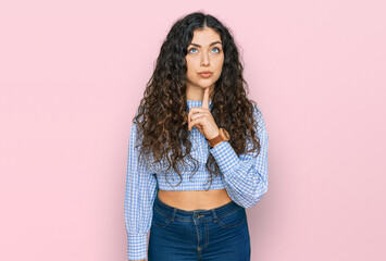 Young hispanic girl wearing casual clothes thinking concentrated about doubt with finger on chin and looking up wondering