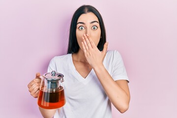 Beautiful woman with blue eyes wearing traditional tea pot covering mouth with hand, shocked and afraid for mistake. surprised expression