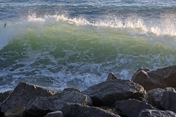 Sea wave during a storm with foam on the background of stones.