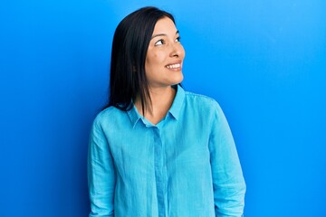 Fototapeta premium Young latin woman wearing casual clothes looking to side, relax profile pose with natural face and confident smile.
