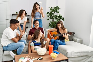 Group of young friends having party playing classical guitar at home.