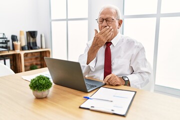 Naklejka premium Senior man working at the office using computer laptop bored yawning tired covering mouth with hand. restless and sleepiness.