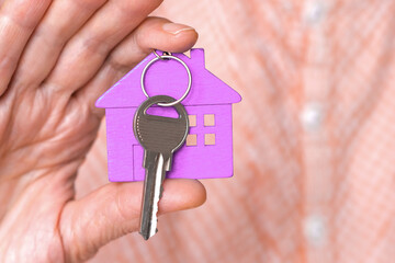 figure of a purple mini house with the keys are in the hand of a man