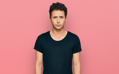 Young handsome man wearing casual black t shirt skeptic and nervous, frowning upset because of...