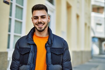 Fototapeta premium Handsome hispanic man with beard smiling happy and confident at the city wearing winter coat