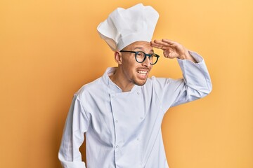 Bald man with beard wearing professional cook uniform very happy and smiling looking far away with...
