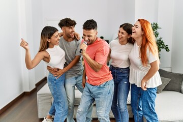 Fototapeta premium Group of young friends having party singing song using microphone at home.