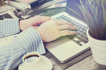 Side view shot of a man's hands using smart phone in interior, rear view of business man hands busy using cell phone at office desk, young male student typing on phone sitting at wooden table, flare