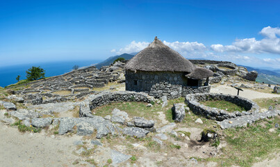 stone walls and thatched roof dwelling in the Celtic fort of Mount Santa Trega with the Atlantic Ocean in the background
 - obrazy, fototapety, plakaty