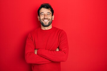 Handsome man with beard wearing casual red sweater happy face smiling with crossed arms looking at...