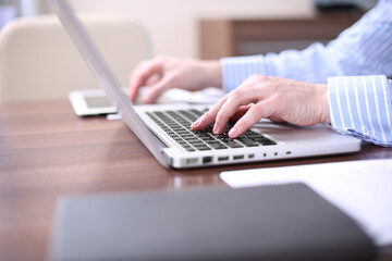 Businessman at work. Close-up top view of man working on laptop while sitting at the wooden desk