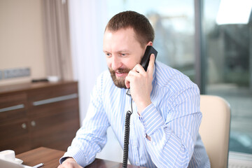 Cheerful man in office answering the phone