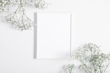 Photo frame and flowers of gypsophila on white background. Flat lay, top view, copy space - obrazy, fototapety, plakaty