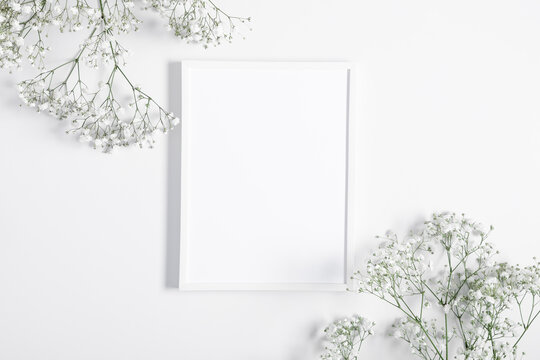 Photo frame and flowers of gypsophila on white background. Flat lay, top view, copy space