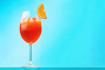 Aperol spritz cocktail on blue background. Glass of cocktail aperol spritz with a slice of orange....