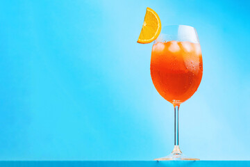 Aperol spritz cocktail on blue background. Glass of cocktail aperol spritz with a slice of orange....