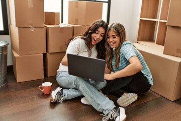 Young beautiul couple drinking coffee and using laptop at new home.