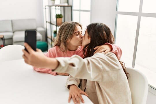 Young couple kissing and making selfie by the smartphone at home.