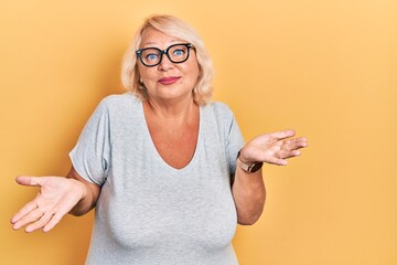 Middle age blonde woman wearing casual clothes and glasses clueless and confused expression with...