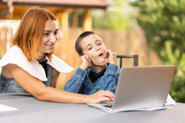 Boy studying from home in an online classroom in the new normal. Schoolboy listens to a lecture and solves problems