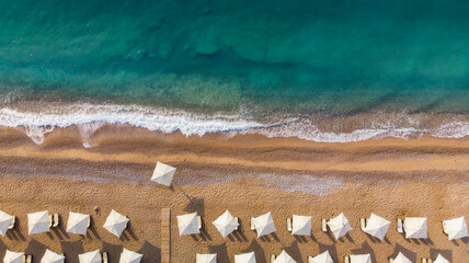 aerial view of an amazing empty white beach with white beach umbrellas and turquoise clear water during the sunrise. Mediterranean sea.