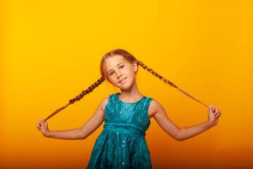 Obraz premium Beautiful portrait of a young girl child with adorable pigtails in her hands. the girl grimaces at the camera 