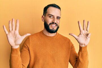 Young man with beard wearing casual winter sweater showing and pointing up with fingers number nine...