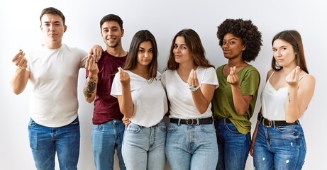Group of young friends standing together over isolated background doing money gesture with hands, asking for salary payment, millionaire business