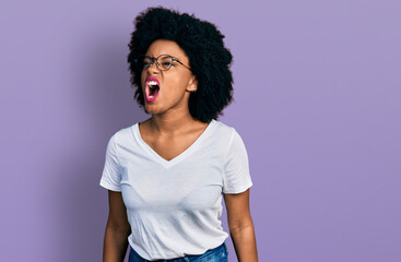 Young african american woman wearing casual white t shirt angry and mad screaming frustrated and furious, shouting with anger. rage and aggressive concept.