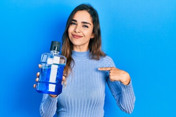 Young hispanic girl holding mouthwash for fresh breath pointing finger to one self smiling happy and proud - obrazy, fototapety, plakaty