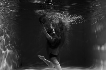 Fototapeta na wymiar Beautiful girl underwater in the pool. Black and white photography, creative and mystical