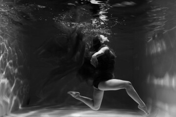 Fototapeta na wymiar Beautiful girl underwater in the pool. Black and white photography, creative and mystical
