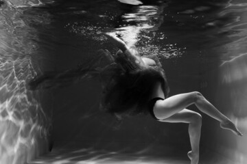 Beautiful girl underwater in the pool. Black and white photography, creative and mystical