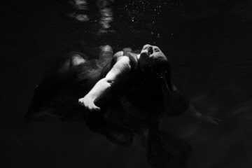Beautiful girl underwater in the pool. Black and white photography, creative and mystical
