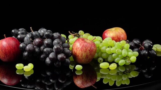 Still life with grapes and apples on a black background.