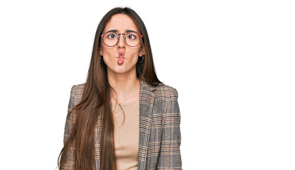 Young hispanic girl wearing business clothes and glasses making fish face with lips, crazy and comical gesture. funny expression.