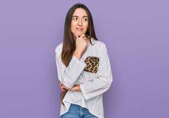 Young hispanic girl wearing casual clothes with hand on chin thinking about question, pensive expression. smiling with thoughtful face. doubt concept.