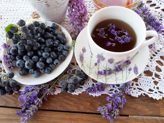 Healthy food. In a white porcelain cup, black lavender tea, a plate of vitamin blueberries and fresh lavender flowers.