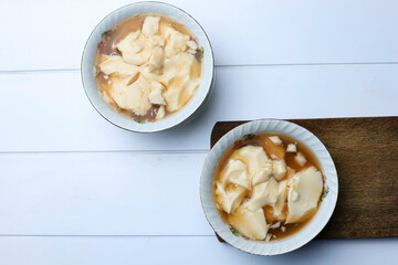 Tahwa or Wedang Tahu or Kembang Tahu, Indonesian Traditional Dessert made from Gingger and Palm Sugar Syrup with Beancurd Made from Soy Bean Milk. Serve on Bowl, Top View with Copy Space for Text