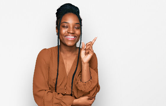 Young african american woman wearing casual clothes with a big smile on face, pointing with hand and finger to the side looking at the camera.